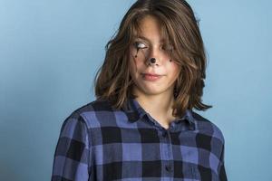 Cute, fashionable, cheeky Caucasian brunette with clown makeup and long hair, dressed in a plaid shirt photo