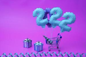 a cart from the supermarket carries inflatable figures with numbers 2022 year photo