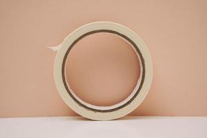 a roll of sticky masking tape on a peach background photo