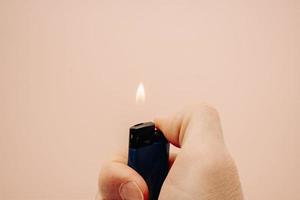 lighter with fire in hand on a peach background photo
