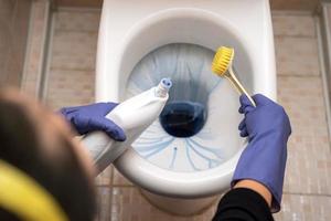 Women's hands cleaning a toilet bowl in a bathroom. A woman cleans the toilet in the bathroom photo