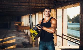 Muscular man with a chainsaw photo