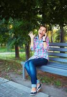 A portrait of a smiling beautiful woman in a park talking on the phone photo