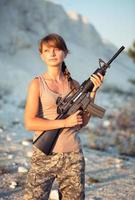 Young female soldier dressed in a camouflage with a gun in the outdoor photo