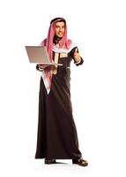 joven sonriente árabe con ordenador portátil aislado en blanco foto