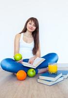 Young brunette with apple reading a book at home photo