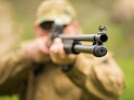 hombre en camuflaje con un escopeta puntería a un objetivo foto