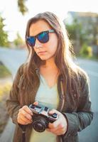 Lifestyle portrait of pretty young fashion brunette in sun glasses on the sun at sunset photo