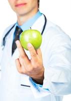 Doctor's hand holding a fresh green apple close-up on white photo