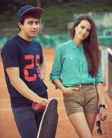 Young couple standing on a skateboard on the tennis court photo