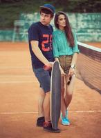 joven Pareja en pie en un patineta en el tenis Corte foto