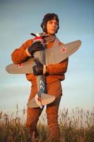 chico en Clásico ropa piloto con un avión modelo al aire libre foto
