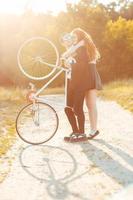 joven elegante chico con niña y el bicicleta al aire libre foto