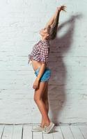 Young beautiful girl in shirt and shorts on a background of a brick wall photo