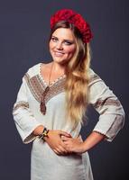 Young pretty smiling girl in Ukrainian costume with a red wreath on her head photo