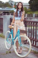 joven esmeradamente vestido mujer con bicicleta, verano y estilo de vida foto
