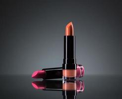 Two bright lipsticks on a black photo