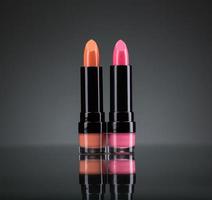 Two bright lipsticks on a black photo