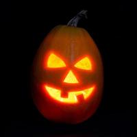 Halloween pumpkin jack-o-lantern candle lit, isolated on black photo