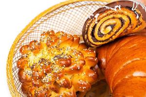 Fresh and tasty buns with with sesame and poppy seeds, bagel with jam and roll with chocolate in a basket photo