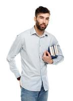 joven barbado sonriente hombre con libros en manos en blanco foto