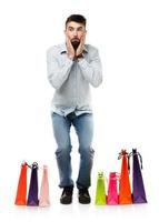 Handsome man with shopping bags is shocked on white background photo