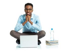 Happy african american college student sitting with laptop on white photo