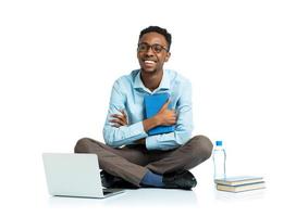 Happy african american college student sitting with laptop on white photo