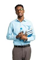 Happy african american college student standing with books and bottle of water in his hands on white photo