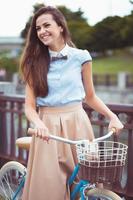 Young beautiful, elegantly dressed woman with bicycle in the park or outdoor photo