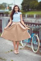 joven hermoso, esmeradamente vestido mujer con bicicleta en el parque o al aire libre foto