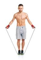 Athletic attractive man jumping on a rope on the white photo