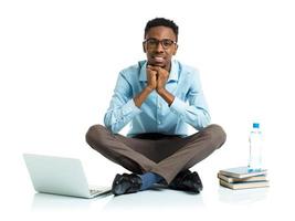 Happy african american college student sitting with laptop on white background photo