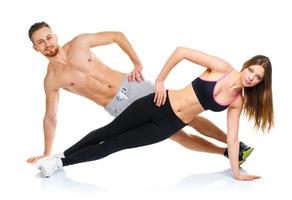 Athletic attractive couple - man and woman doing fitness exercises on the white photo