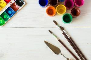 Painting set with brushes, paints, watercolor, acrylic paint on a white wooden background top down view photo