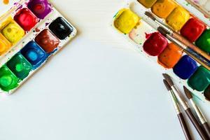 Painting set with brushes, paints, watercolor, acrylic paint on a white wooden background top down view photo