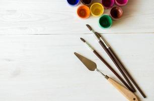 Painting set with brushes, paints, watercolor, acrylic paint on a white wooden background top down view photo