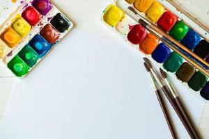 Painting set with brushes, paints, watercolor, acrylic paint on a white wooden background top down view photo