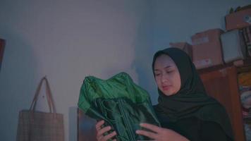 un' musulmano donna Tenere un' verde vestito e guardare confuso quando lei sega lui video