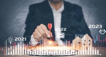 2021-2023  with Targeting the business concept, Businesswoman hand holding red dart to the virtual target dartboard, Executive marketing, investment goal and target for business investment concept, photo