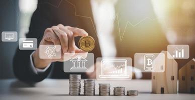 Businessman hand holding bitcoin on Coins stack on the wooden table, Saving ideas and investment budget, market financial Financial growth concept with golden Bitcoins ladder on the chart background photo