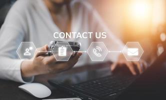 Communication and Contact us or Customer support hotline people connect. Hand using a laptop and touching on virtual screen contact icons, email and address, live chat with internet wifi. photo