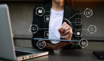 Web hosting concept, woman using computer, tablet and presses his finger on the virtual screen inscription Hosting on desk, Internet, business, digital technology concept. photo