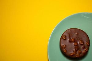 A picture of single homemade chocolate tart on yellow background. Same colour subject and background concept photo