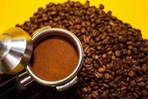An open bag of fresh coffee beans. Holder filter with ground coffee for coffee machines. Selective focus. Close up. photo
