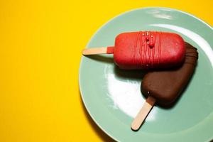 Chocolate cake pops in the form of ice cream on a stick. On a plate on a yellow background. Concept food, sweets. Top view. photo