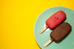 Cake in the form of ice cream on a stick among flowers, close-up. Cheesecake on a stick. Ice cream in glaze photo