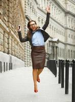 Delighted business woman jumping for joy while talking on the smart phone photo