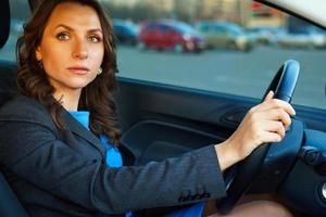 Woman sits in a car in a parking near a shopping center photo