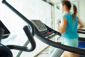 Woman running on treadmill in gym photo